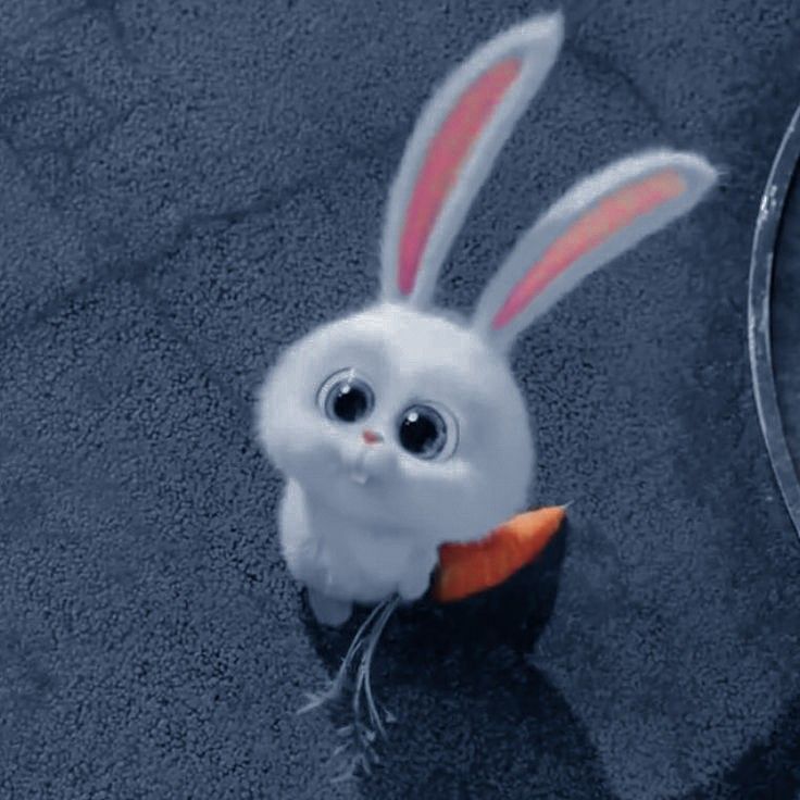 a white rabbit with an orange carrot in it's mouth