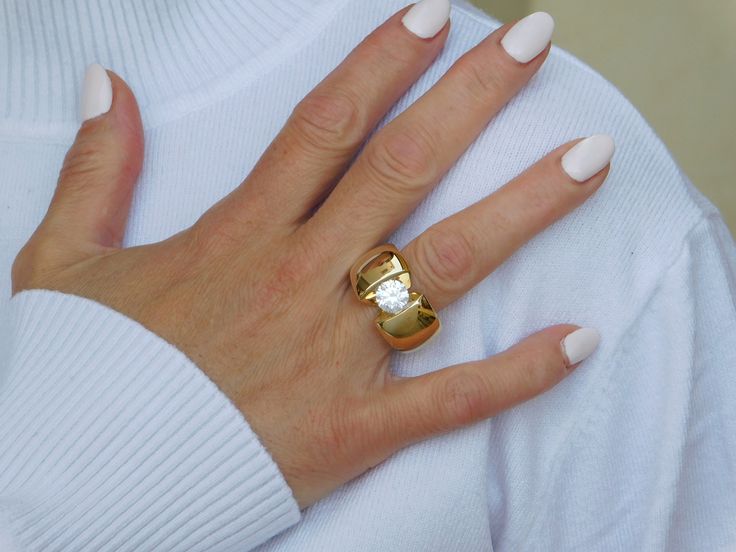 a woman's hand with white nails and a gold ring