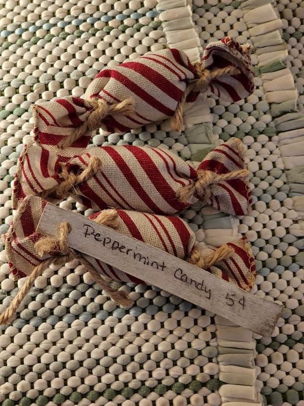 two red and white striped bows tied together on a woven tablecloth with a sign that says peppermint candy