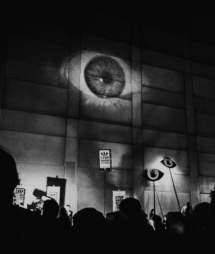 people are standing in front of a wall with an eye projected on it