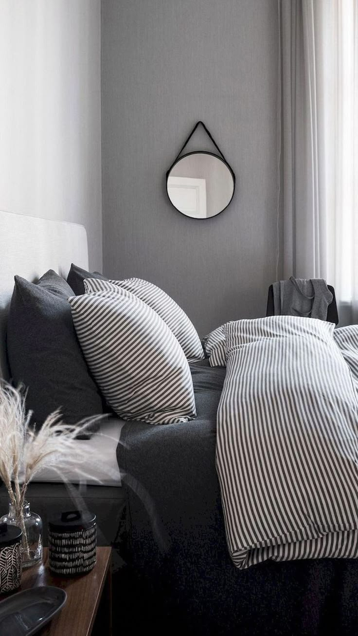 a bed with black and white sheets in a bedroom next to a window on the wall