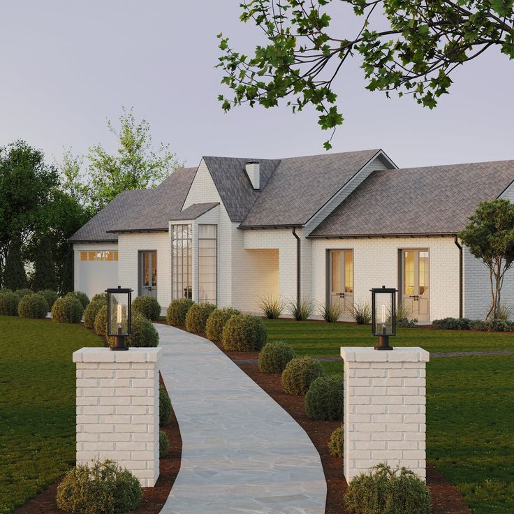 a white brick house with landscaping and trees in the front yard at dusk or dawn