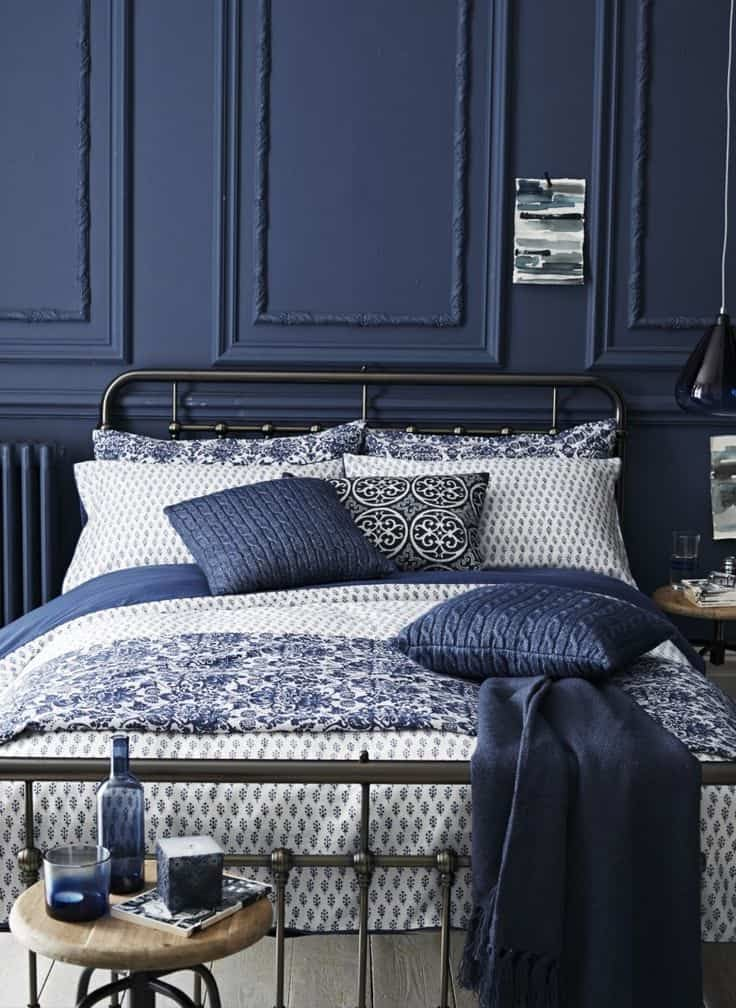 a bedroom with blue walls and white bedding