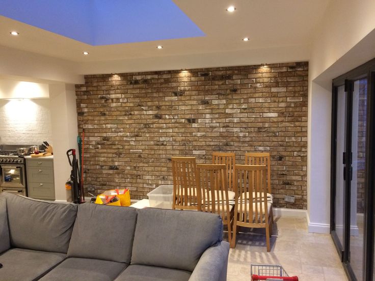 a living room filled with furniture and a brick wall behind the couch is a dining table