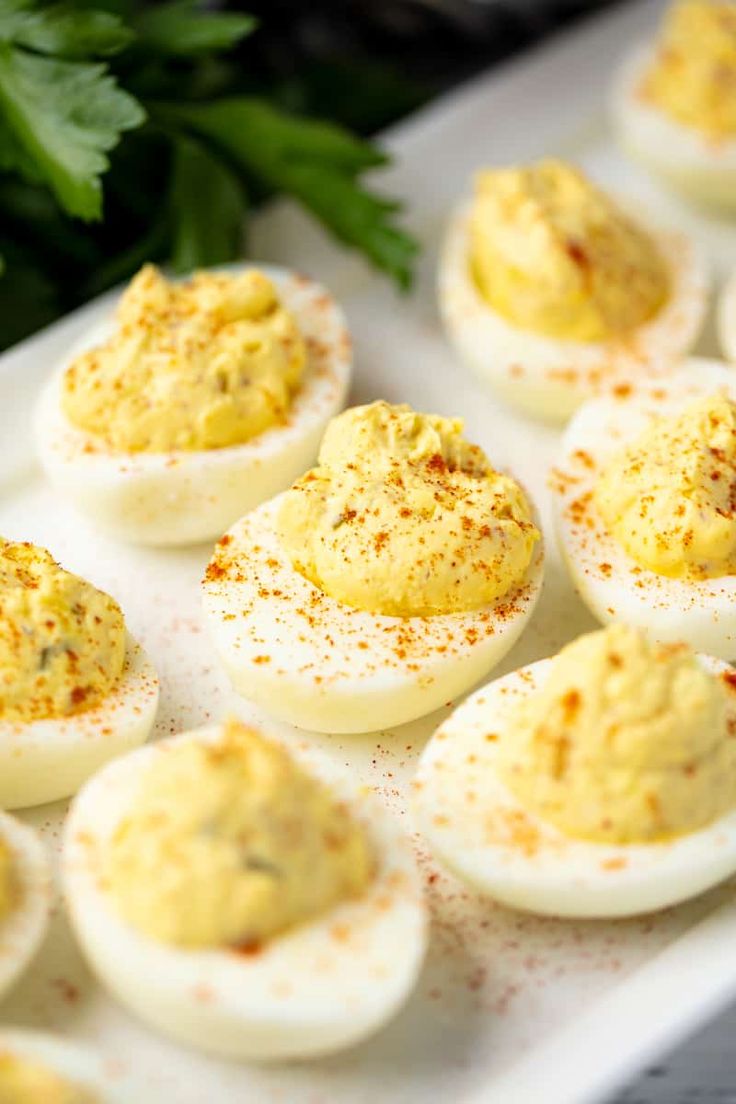 deviled eggs with mustard and parsley on a baking sheet