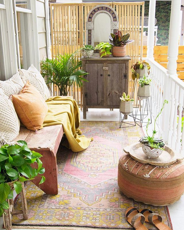 an outdoor patio with plants and potted plants on the side walk, next to a wooden bench