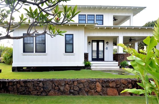 a white house sitting on top of a lush green field next to a stone wall