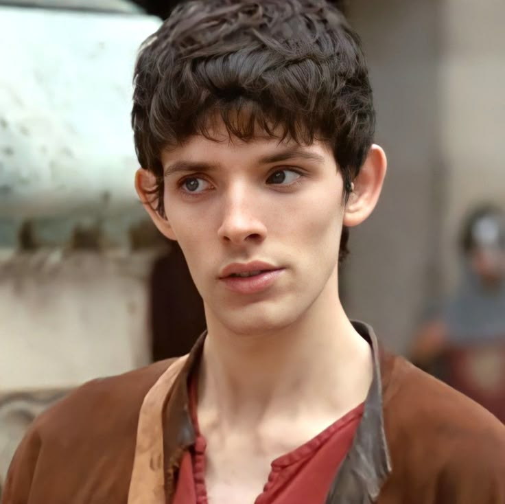 a close up of a person wearing a brown jacket and red shirt with his eyes wide open