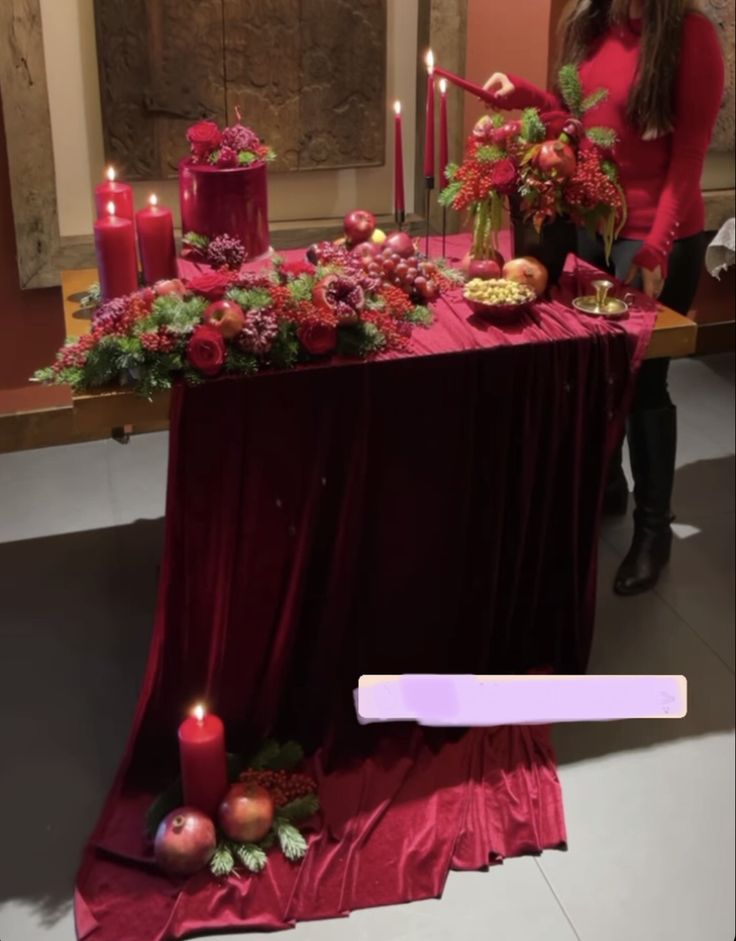 a woman standing next to a table covered in flowers and candles