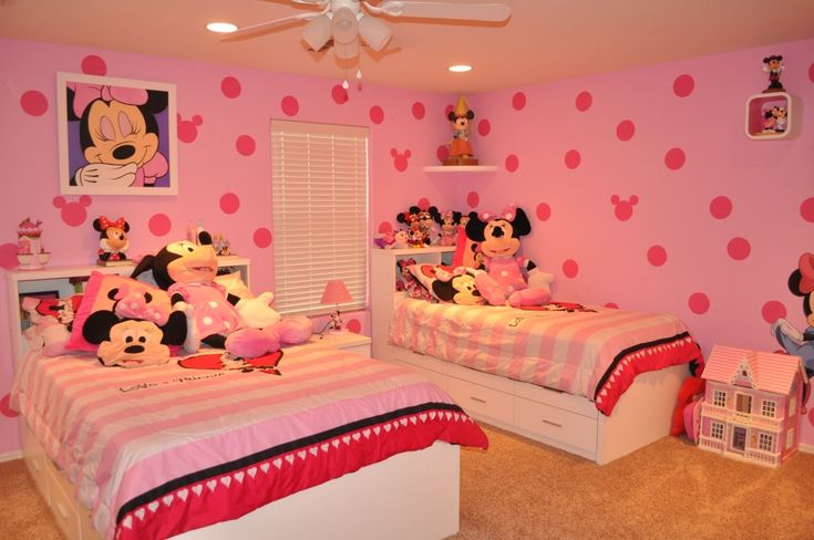 a bedroom decorated in pink and white with minnie mouses on the wall, two twin beds