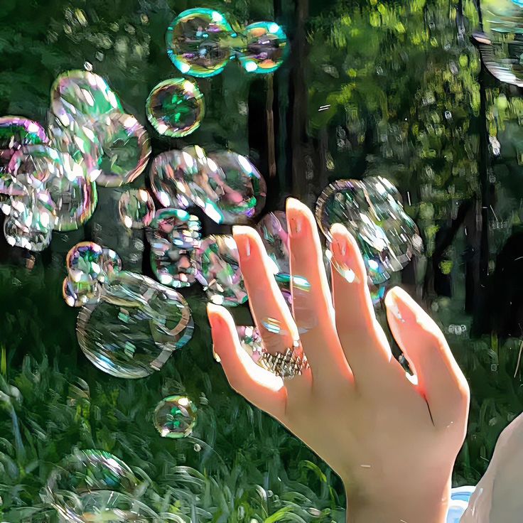 a woman blowing bubbles in the air with her hand on top of it and trees behind her