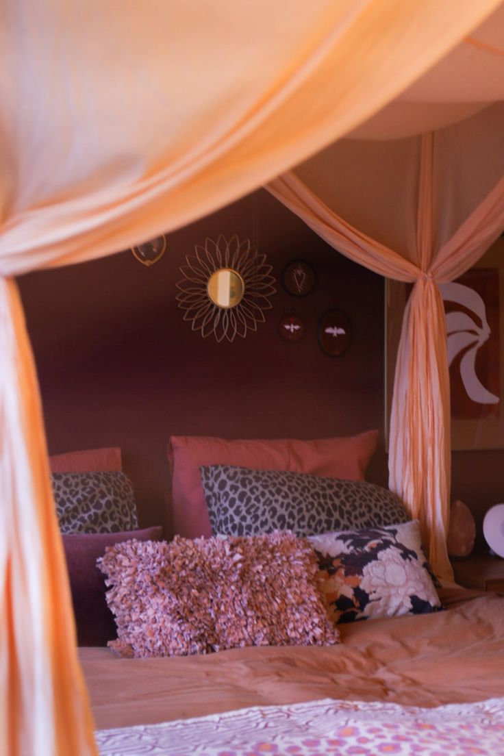 the canopy bed is made up with pink and purple sheets, pillows, and throw pillows