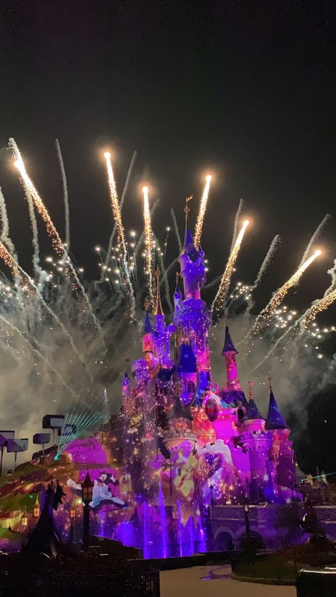 fireworks are lit up in the sky above a castle