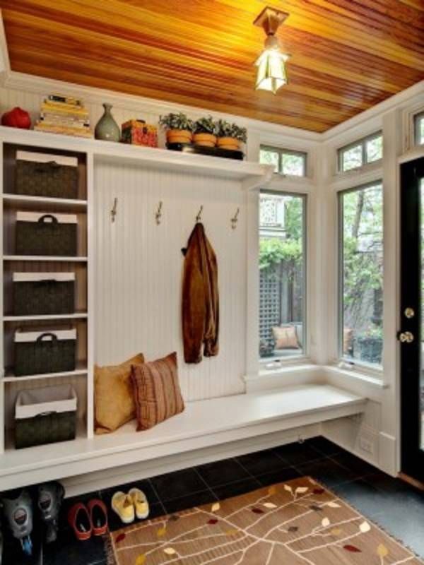 a white bench sitting under a window next to a black door and some shelves with items on it