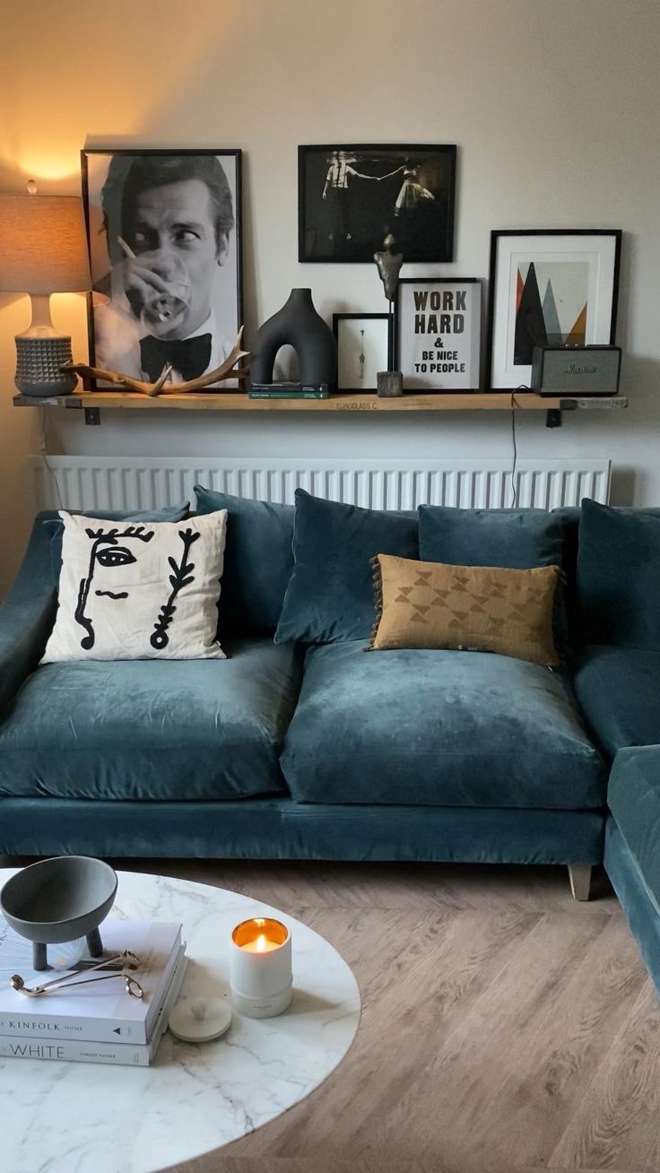 a living room with blue couches and pictures on the wall above them, along with a round coffee table