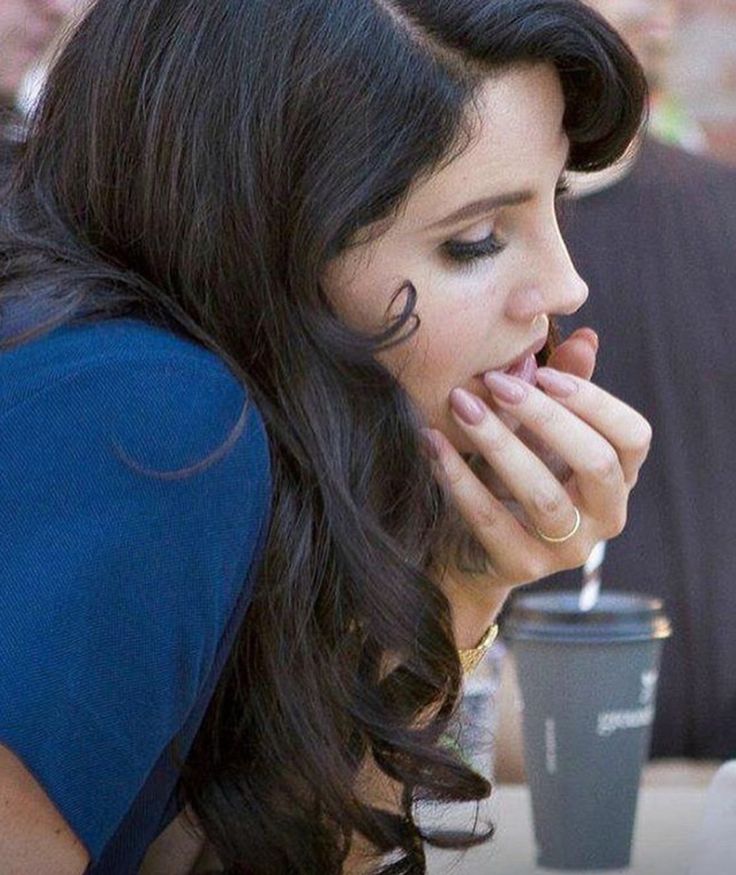 a woman sitting at a table with her hand on her face and looking down while eating food