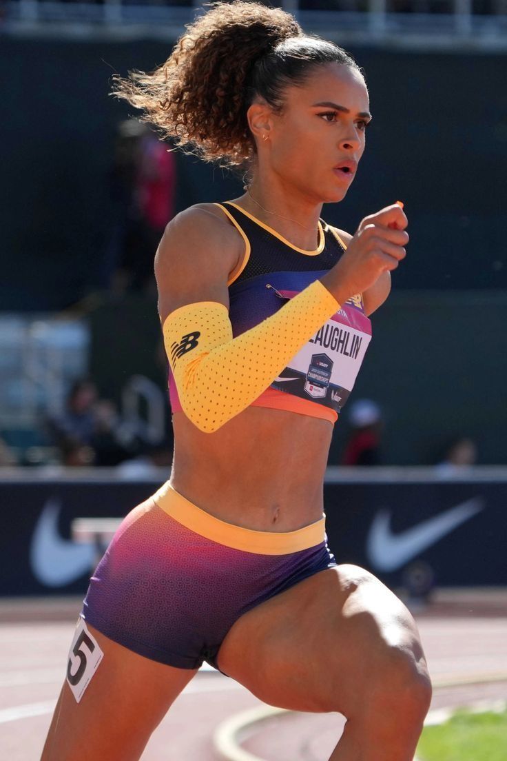 a woman running on a track with her arm in the air