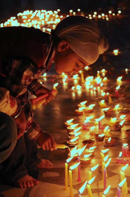 a person kneeling down in front of a bunch of lit candles