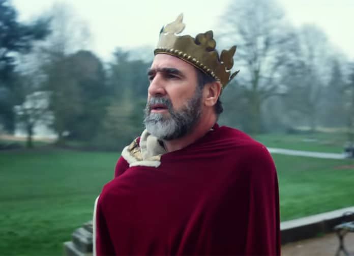 a man with a crown on his head wearing a red cape and holding a bird