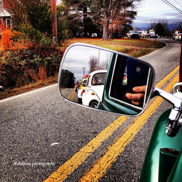 a person's hand is reflected in the side mirror of a motor scooter