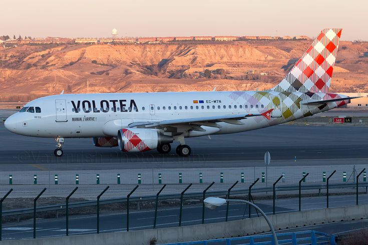 an airplane that is on the runway near some hills and mountains in the back ground