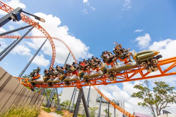 an amusement park ride with people on it's roller coaster in the day time