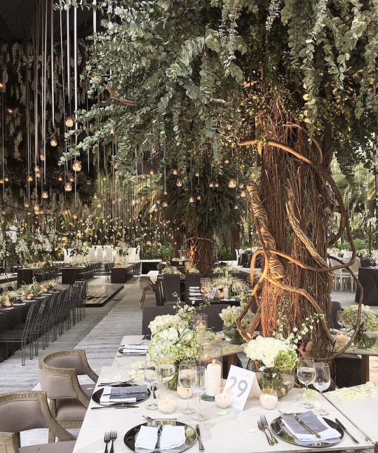 an outdoor dining area with tables, chairs and chandeliers hanging from the ceiling