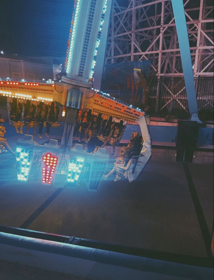 an amusement park ride at night with people sitting on the rides and looking out the window