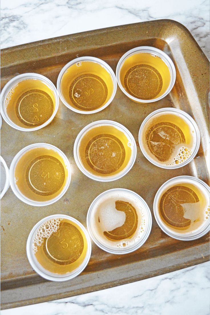 a tray filled with lots of cups sitting on top of a marble countertop covered in liquid