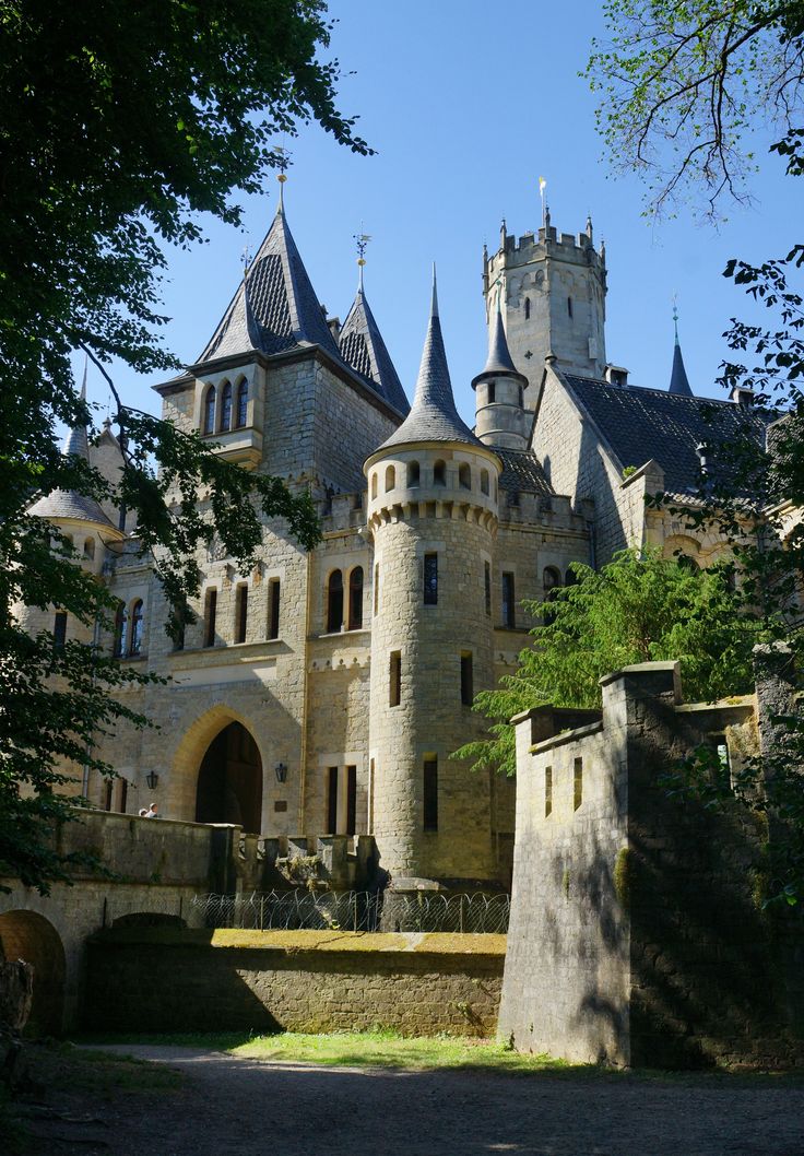 an old castle with turrets and towers is shown from the outside, surrounded by trees