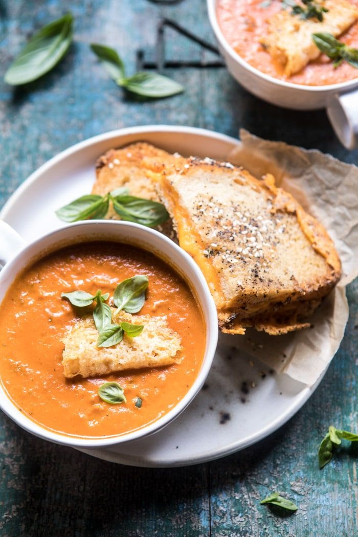 two bowls of soup with toast on the side and garnished with basil leaves