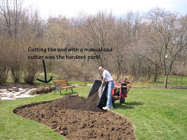 a man is digging dirt in the yard with a lawnmower and tractor behind him