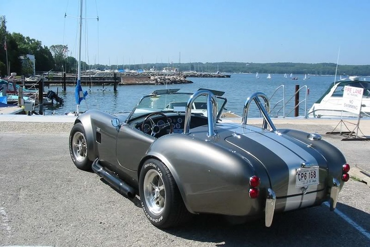 an antique sports car is parked near the water