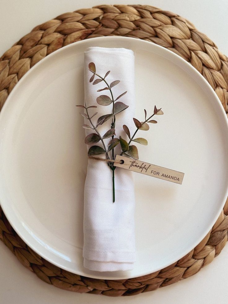 a white plate topped with a napkin and a small plant on it's side