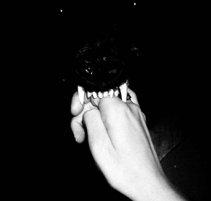 a person holding something in their hand with teeth on it's face at night