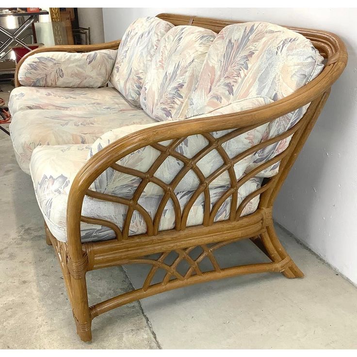 a wicker couch sitting on top of a cement floor next to a white wall