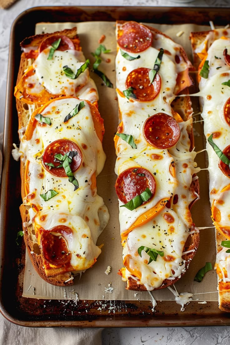 several slices of pizza with cheese and pepperoni on a baking sheet, ready to go into the oven