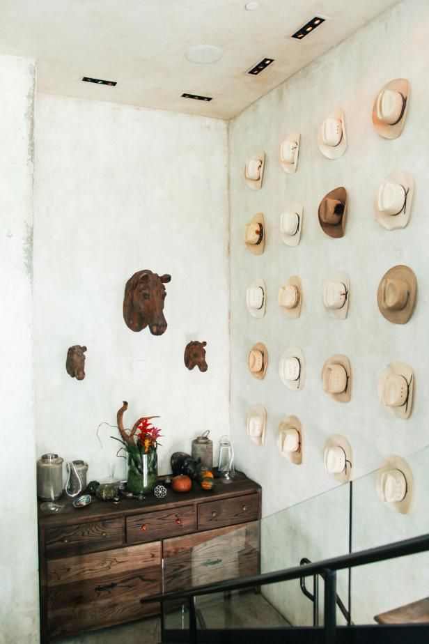 a room with many hats on the wall and a dresser in front of some stairs