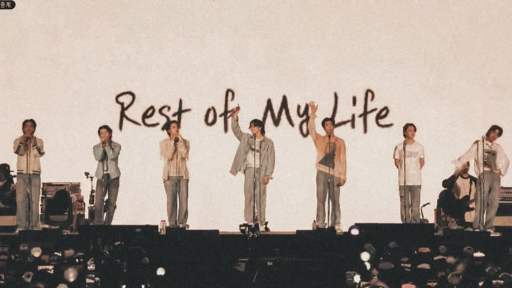 a group of men standing on top of a stage in front of a wall with the words rest of my life written on it