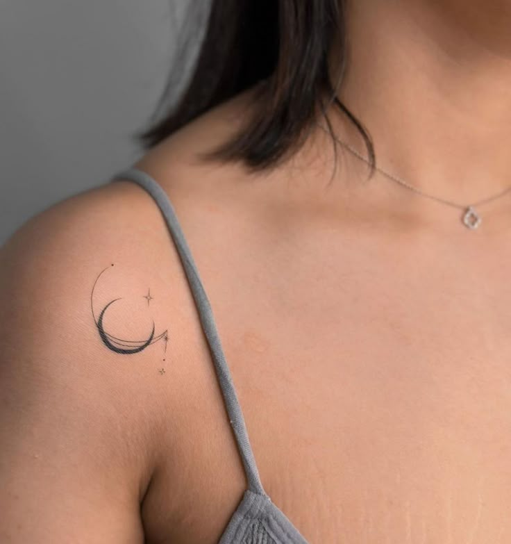 a woman with a small crescent tattoo on her left shoulder and right arm behind her back