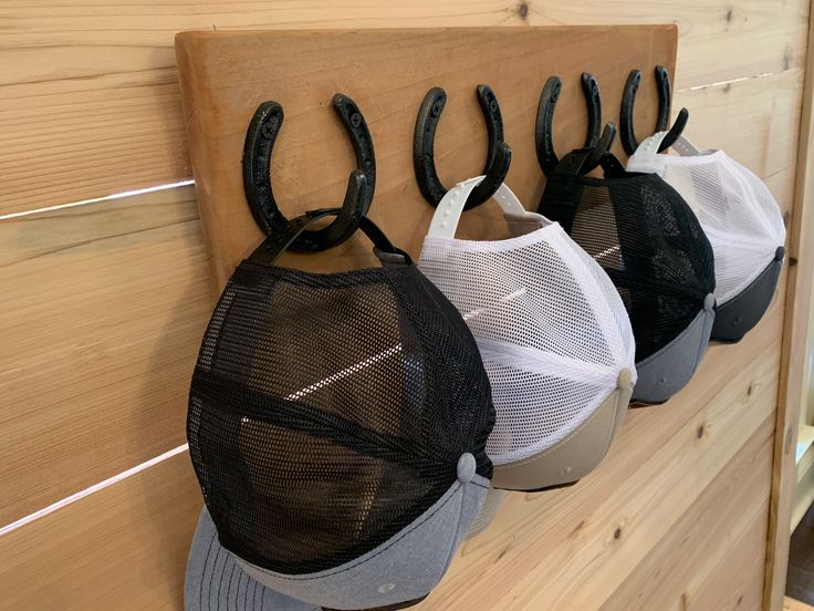 three hats hanging from hooks on a wooden wall