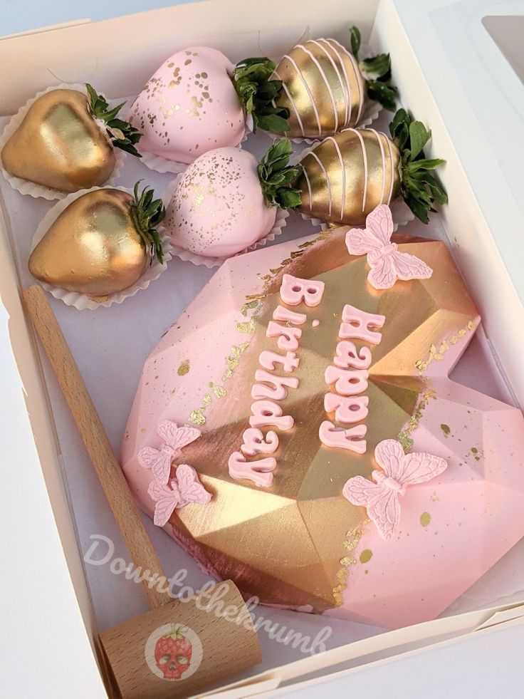 a pink and gold birthday cake in a box