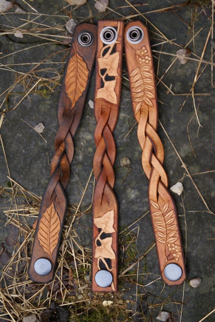 three wooden spoons with eyes and leaves on them sitting in the grass next to some twigs