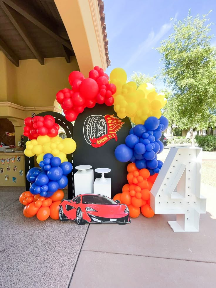 a bunch of balloons that are on the ground near a car and number four sign