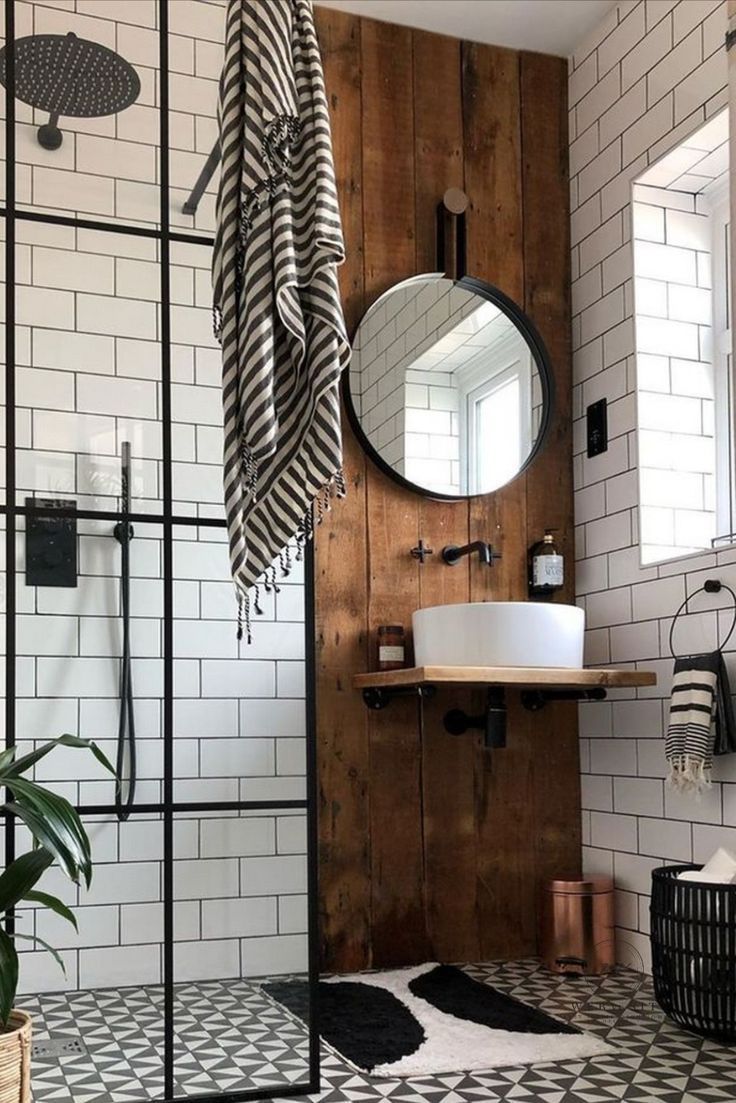 a bathroom with black and white tile, wood paneling and a round mirror on the wall