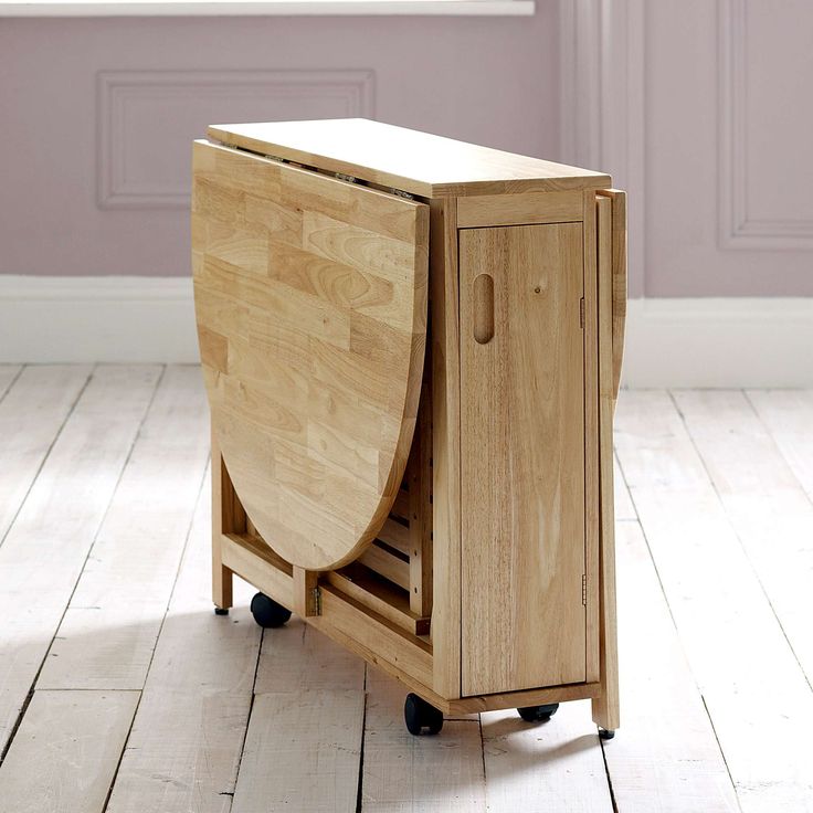 a small wooden cabinet on wheels in the middle of a room with hardwood flooring