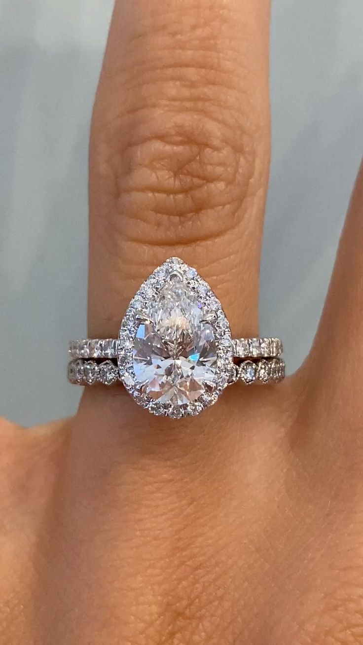 a woman's hand with a diamond ring on top of her finger and an engagement band