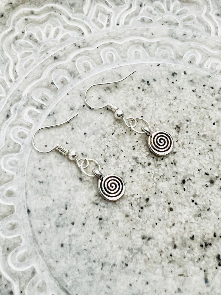 Experience the elegance of simplicity with these minimalist earrings featuring small silver swirls suspended from silver ear wires. Each pair captures the essence of contemporary chic and understated beauty. The delicate silver swirls add a touch of artistic flair to your everyday style, making them a versatile addition to your jewelry collection.  The spiral is a symbol of sacred geometry that represents continual growth, evolution, and transformation. It mirrors nature, from the unfolding of a fern frond to the galaxies spiraling in space. Spirals symbolize the journey from the center of being, expanding outward, and then returning to oneself, symbolizing both progress and a return to source. The spiral encourages us to embrace change, learn from our experiences, and strive for spiritual Nickel Free Silver Swirl Earrings, Minimalist Sterling Silver Swirl Earrings, Minimalist Silver Spiral Earrings, Minimalist Silver Swirl Earrings, Silver Swirl Earrings, Minimalist Spiral Nickel-free Earrings, Nickel-free Spiral Minimalist Earrings, Minimalist Swirl Earrings As Gift, Minimalist Swirl Earrings Gift