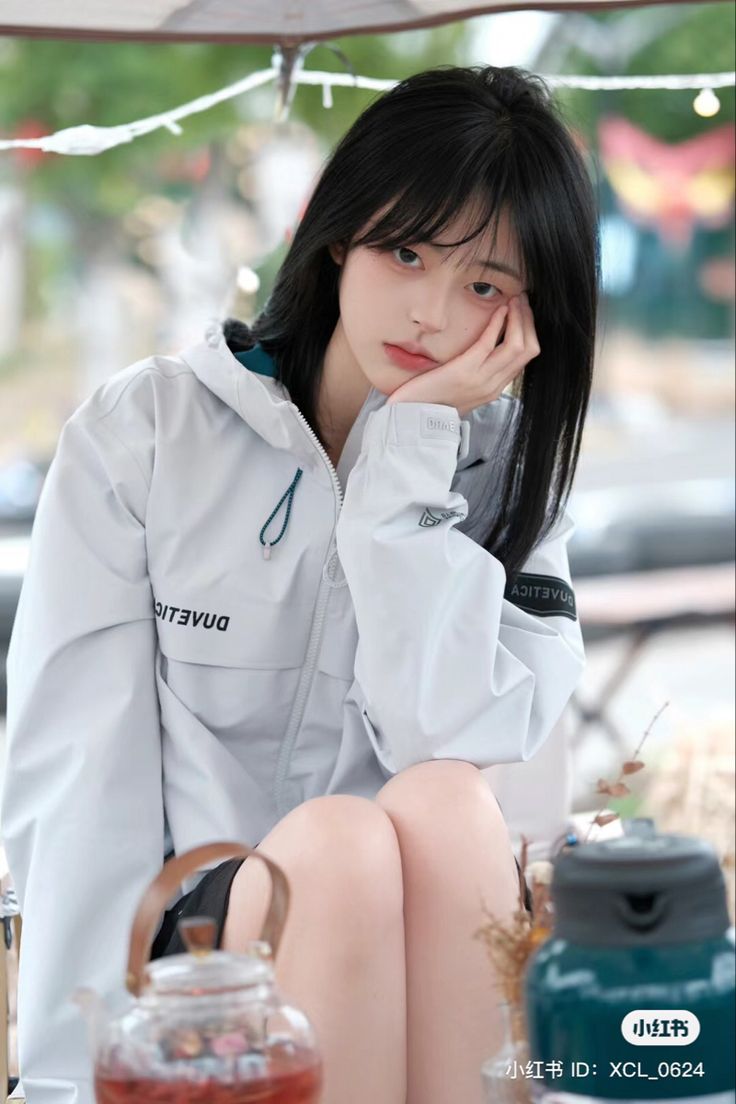 a young woman sitting on top of a table next to a jar filled with liquid