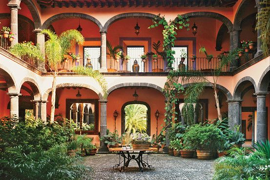 an outdoor courtyard with potted plants and tables in the center, surrounded by greenery